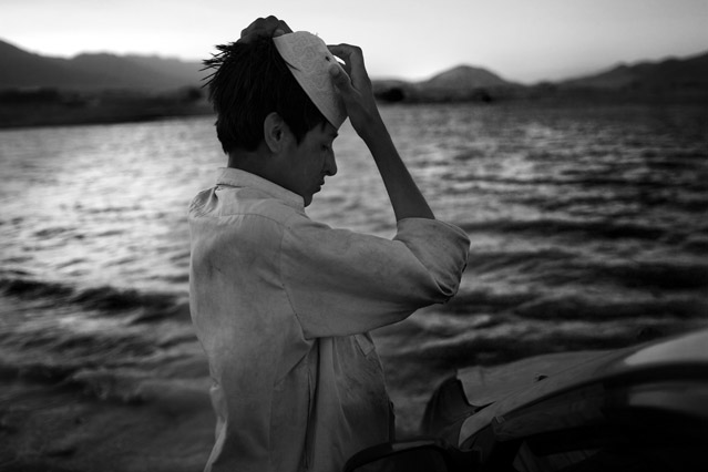 100716021055 Shir Gul adjusts his cap after washing a car for money on the shores of the Qargha Reservoir outside Kabul.